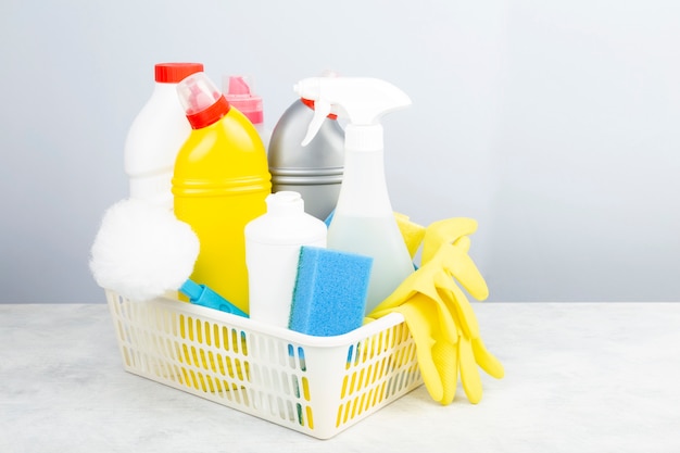 Vários detergentes e agentes de limpeza, esponjas, guardanapos e luvas de borracha, fundo cinza. Copie o espaço
