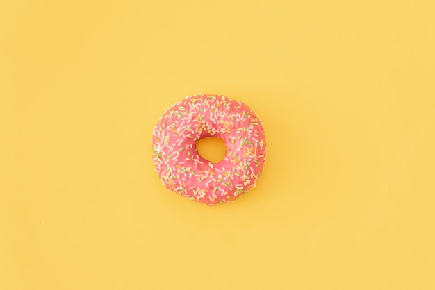 Vários donuts decorados em movimento caindo sobre fundo rosa. Anéis de espuma doces e coloridos que caem ou que voam no movimento.