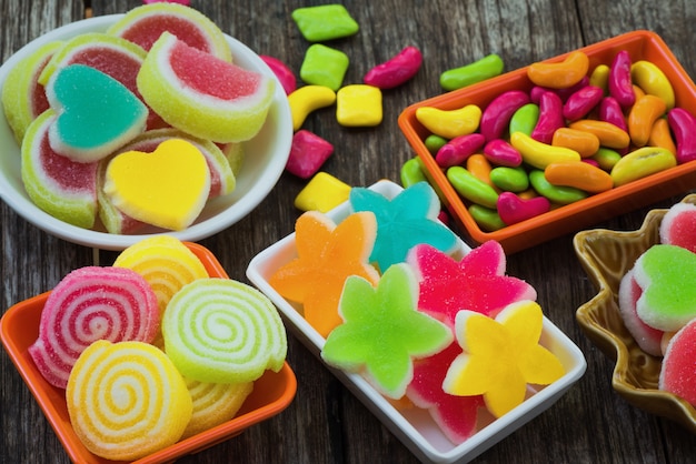 Foto varios dulces de colores azucarados en contenedor en tablón de madera viejo