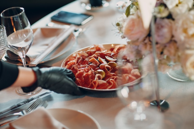 Varios embutidos en un plato con flores blancas en la mesa