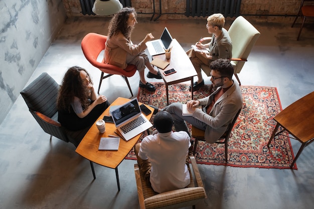 Foto varios empresarios interculturales interactuando por mesas en la oficina