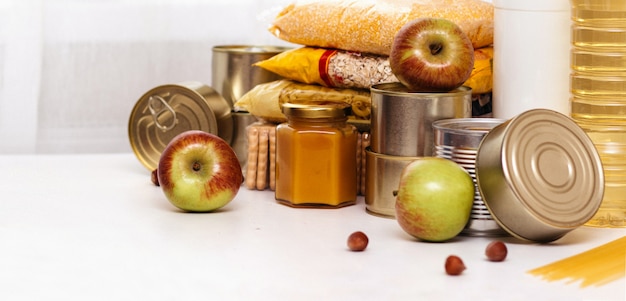 Foto vários enlatados, massas e cereais em uma mesa branca. doação de alimentos ou conceito de entrega de alimentos.