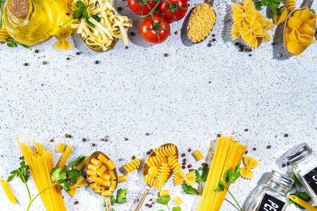 Varios fideos de espagueti secos pasta en cucharas sobre fondo de mesa blanca Diferentes tipos de formas pasta italiana cruda con hierbas aceite de oliva tomates especias para cocinar vista superior espacio de copia