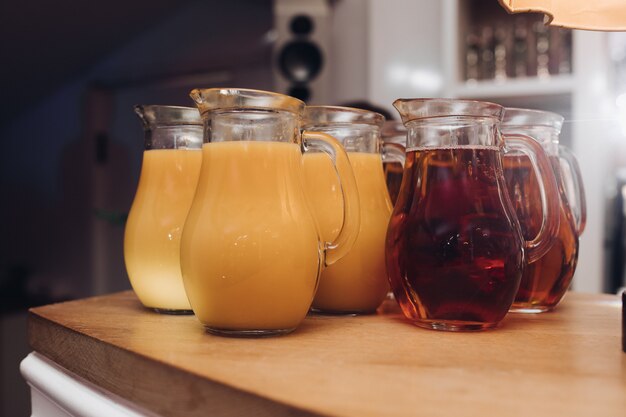 Vários frascos de suco de laranja e bagas na mesa de madeira