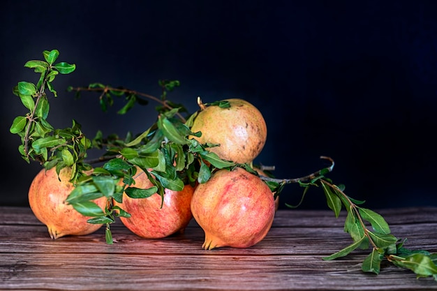 Vários frutos maduros de romã com folhas de romã