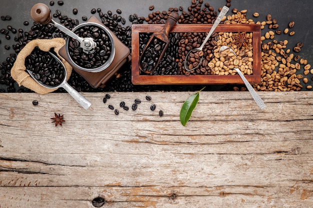 Varios de los granos de café tostados en caja de madera con configuración manual de molinillo de café en madera en mal estado.