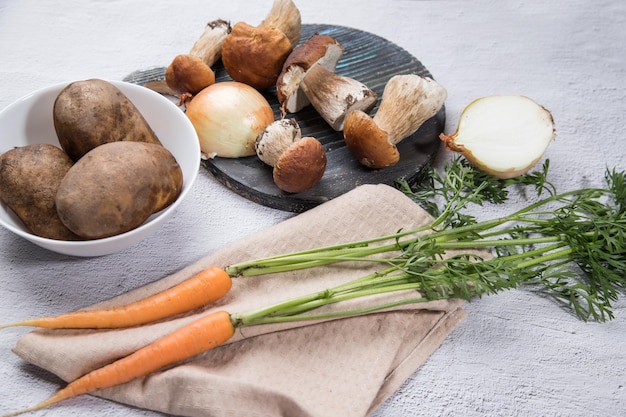 Vários ingredientes para a preparação de cogumelos porcini florestais são dispostos em um fundo leve