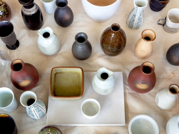 Foto varios jarrón de cerámica de colores dispuestos sobre tela de percal blanco, vista superior. jarrón de cerámica vacío.