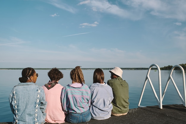 Foto varios jóvenes amigos disfrutando de un día soleado en el muelle