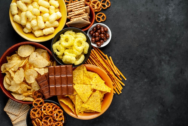 Vários lanches e chocolate em uma mesa preta