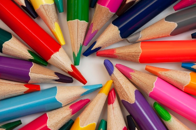 Vários lápis de madeira multicoloridos estão dispostos em um círculo em um fundo branco