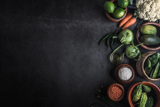 Vários legumes em uma mesa preta com espaço para uma mensagem