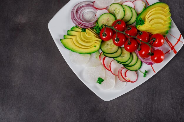 Foto vários legumes frescos abacate tomates frescos, pepino, cebola no fundo de madeira