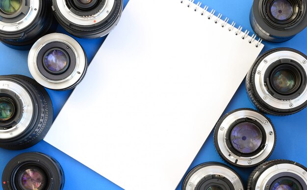 Varios lentes fotográficos y libreta blanca.