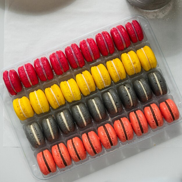 Foto varios macarons coloridos o macarons franceses en una fila en una caja de regalo dulce dulce a base de merengue hecho con clara de huevo azúcar glasé azúcar granulada harina de almendras y colorante alimentario de cerca