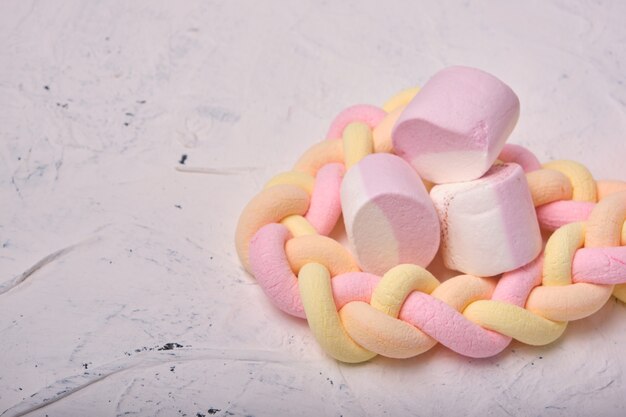 Foto vários marshmallows em um fundo branco, marshmallows trançados longos, marshmallows com sabores de frutas, espaço para cópia