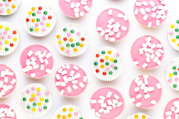 Vários muffins coloridos bem decorados em uma vista superior de fundo branco