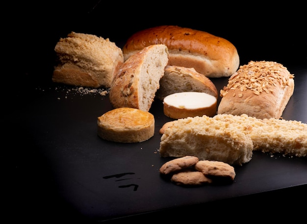 Foto vários pães e bolos com produtos de biscoitos de queijo, gergelim e castanhas em um menu de padaria de mesa preta