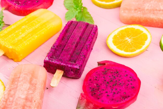 Foto vários picolés de frutas frescas colocados no fundo da placa de madeira