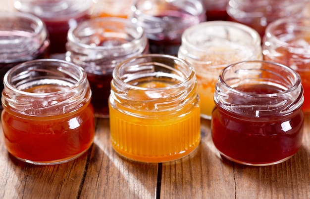 Foto vários potes de geléia de frutas na mesa de madeira