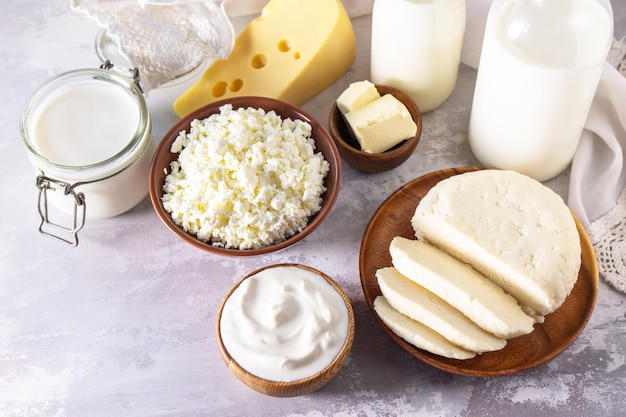 Varios productos lácteos frescos, leche, crema agria, requesón, yogur y mantequilla en una encimera de piedra clara