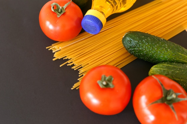 Foto vários produtos. espaguete, macarrão, tomate, pepino e óleo de girassol vegetal.