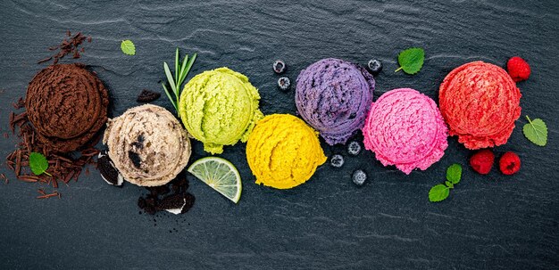 Foto varios sabores de helado bola de arándanos lima pistacho almendra naranja chocolate y vainilla establecido en fondo de piedra oscura verano y dulce concepto de menú