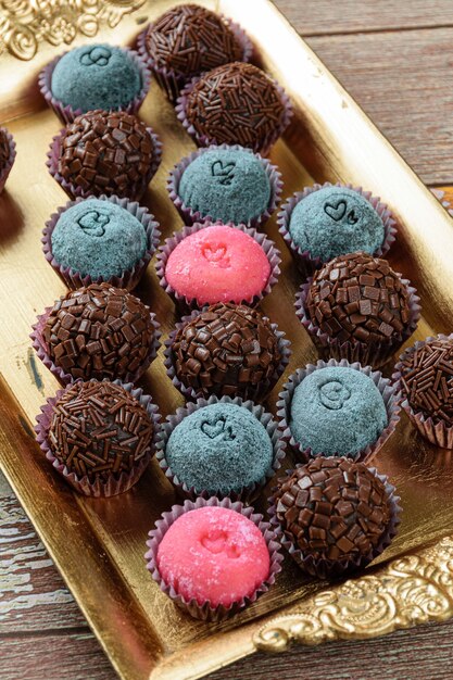 Foto varios tipos de brigadeiro alineados en una bandeja dorada. dulce tradicional brasileño.