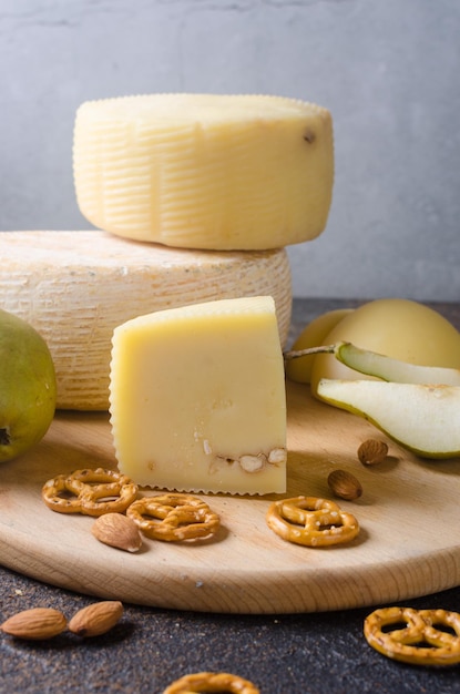 Varios tipos de cabezas y piezas de queso en una tabla de madera