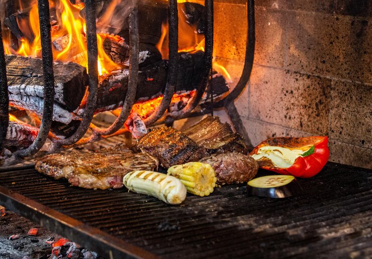 Foto varios tipos de carne, pimienta, berenjenas de maíz y plátanos asados en una parrilla