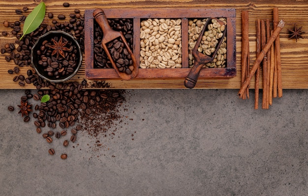Vários tipos de grãos de café torrados em caixa de madeira com moedor de café manual configurado em madeira surrada.
