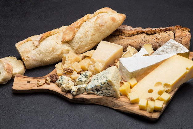 Foto vários tipos de queijo e pão na placa de madeira