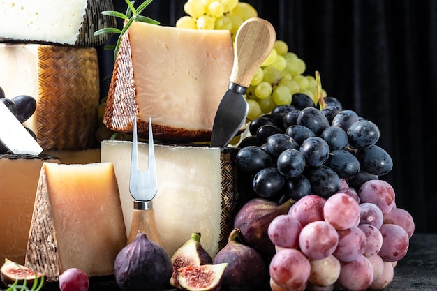 Vários tipos de queijo pedaços tradicionais da itália francesa e queijo manchego espanhol com uvas e figos servidos em mesa de madeira