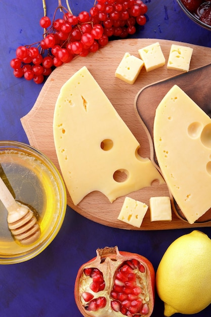 Vários tipos de queijos com frutas e bagas sobre fundo azul Queijo azul e queijo duro amarelo em tábuas de madeira fechadas