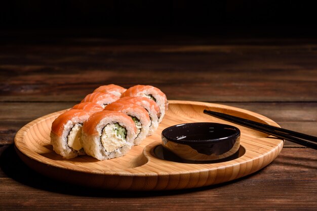 Vários tipos de sushi serviram em um escuro. Rolo com salmão, abacate, pepino. Menu de sushi. Comida japonesa
