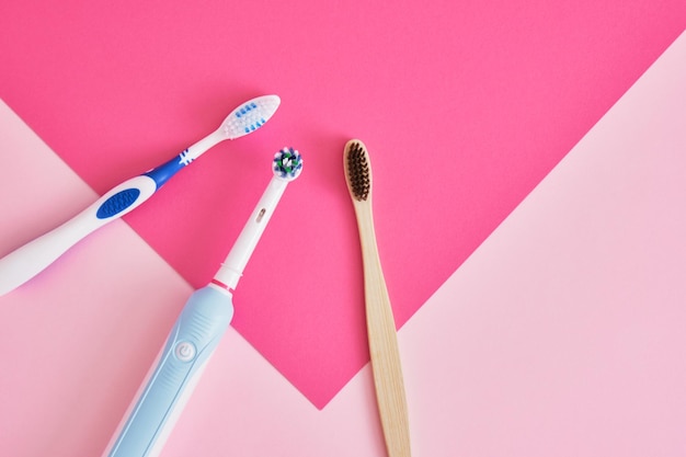 Varios tipos diferentes de cepillos de dientes sobre un fondo rosa