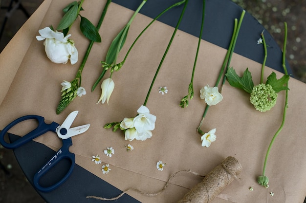 Vários tipos diferentes de flores brancas dispostas em papel pergaminho sobre uma mesa no jardim