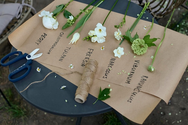 Vários tipos diferentes de flores brancas dispostas em papel pergaminho sobre uma mesa no jardim