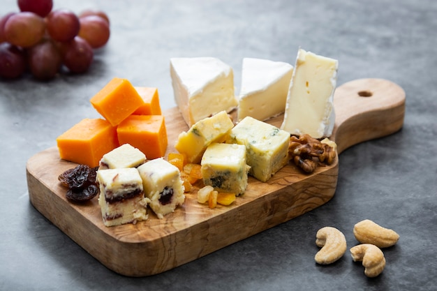 Varios tipos diferentes de lonchas de queso, mezcla de queso sobre tabla para cortar madera.