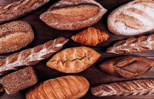 Varios tipos de pan de panadería - hogazas crujientes rústicas frescas de pan y baguette sobre fondo blanco.