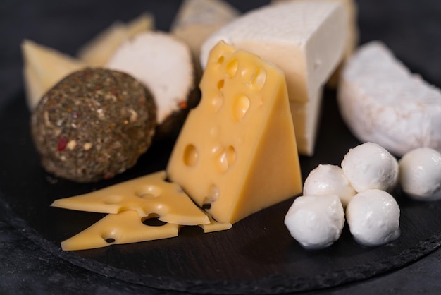 Varios tipos de queso delicioso sobre un fondo negro. Un manjar de élite. Productos lácteos fermentados.