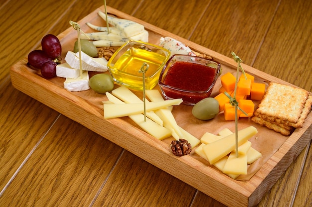 Varios tipos de queso sobre tabla de cortar de madera, vista superior.