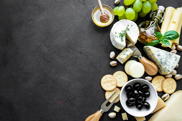 Varios tipos de quesos, uvas, miel y snacks.