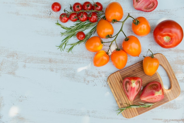 Varios tomates coloridos y hierba de romero en un azul claro