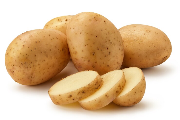 Varios tubérculos de patatas tiernas se encuentran sobre un fondo blanco. Las patatas se cortan en trozos. Aislado.