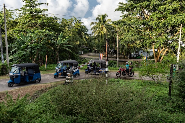 Vários tuk tuks ficam na estrada perto da passagem ferroviária