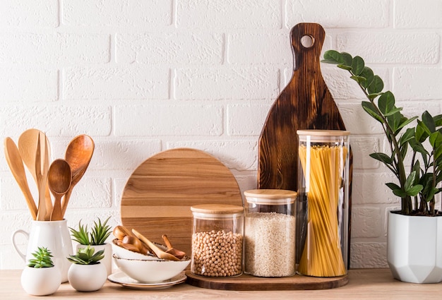 Varios utensilios de cocina y recipientes para almacenar productos a granel en una encimera de madera con una planta en maceta decoración de cocina elegante primer plano