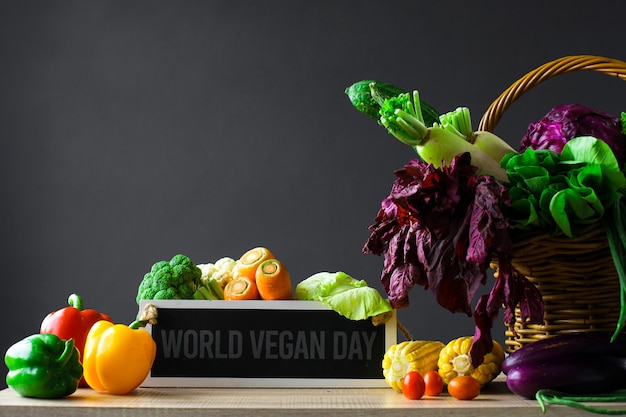 Vários vegetais frescos coloridos com papel timbrado diz o dia mundial do veganismo na mesa de madeira