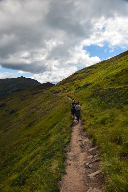 Varios viajeros caminando por la cresta hasta la cima de la montaña contra el cielo azul