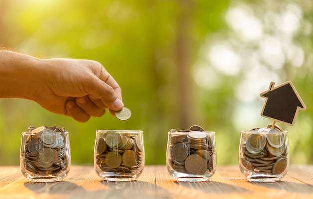 La varita puso la moneda en un frasco transparente sobre la mesa de madera. Ahorro de dinero para el concepto de hogar